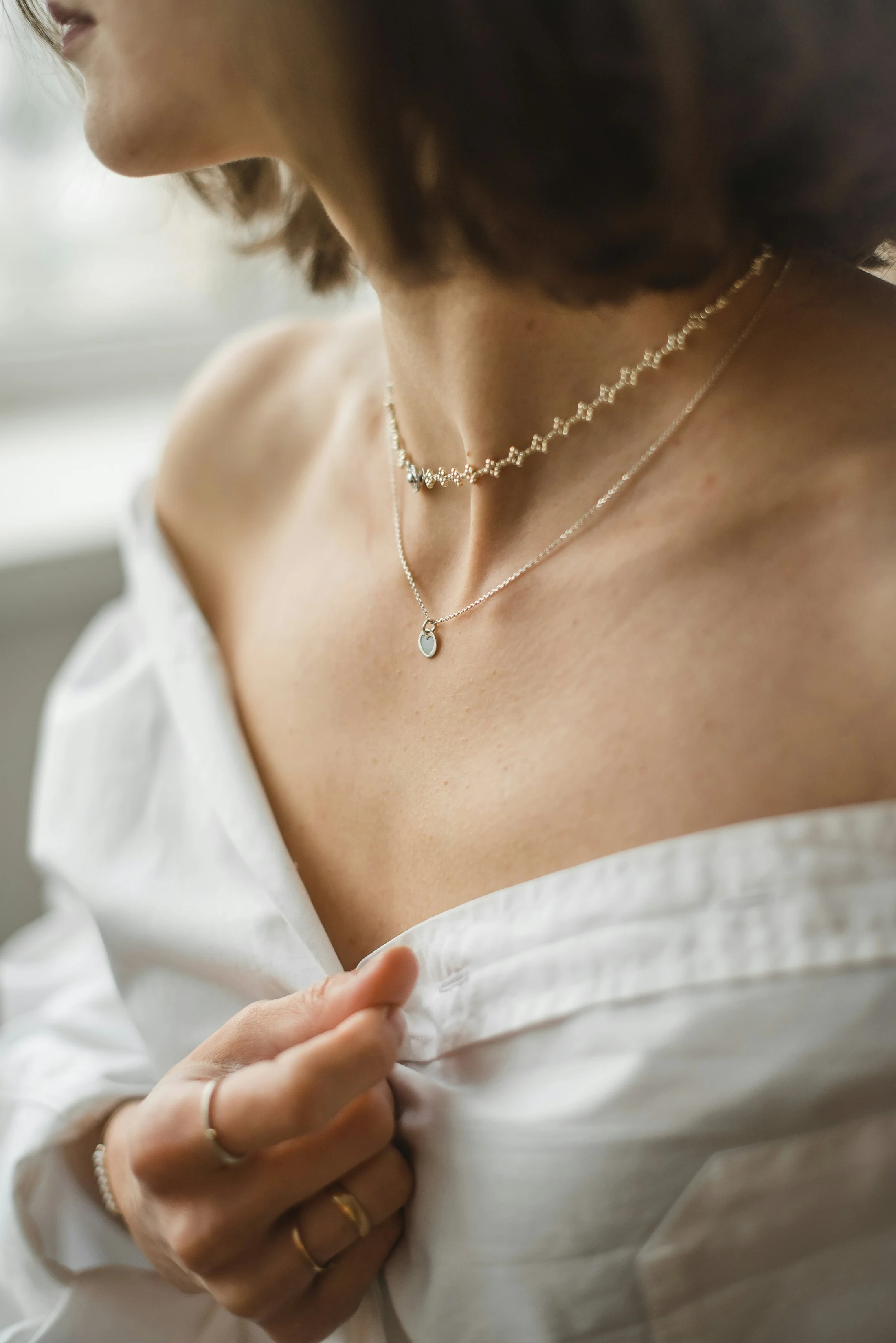 Delicate layered necklaces worn with a white blouse